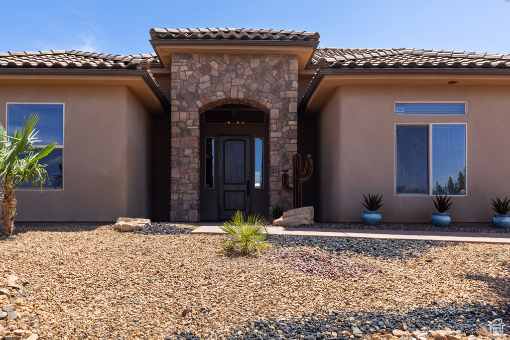 Property entrance with a tile roof, stucco siding, and stone siding