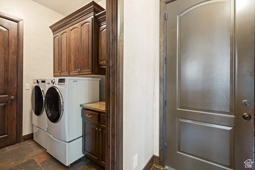 Laundry area with washing machine and clothes dryer, stone tile flooring, and cabinet space