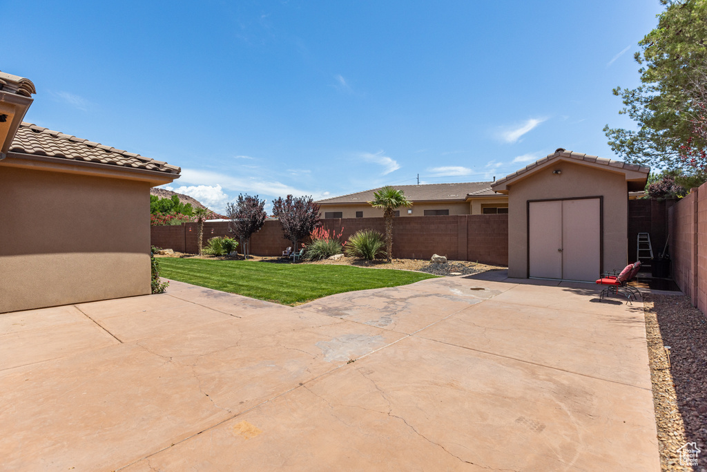 Fenced backyard with a patio area and a storage unit