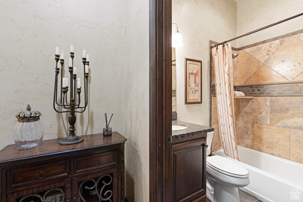 Full bath featuring vanity, shower / bathtub combination with curtain, and a textured wall