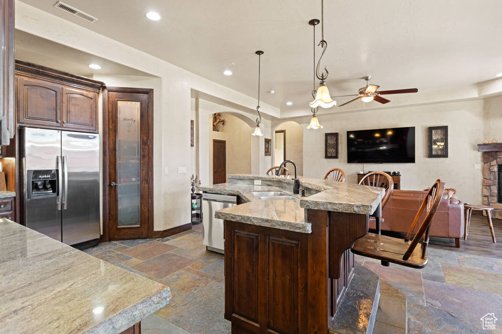 Kitchen with appliances with stainless steel finishes, stone tile flooring, arched walkways, ceiling fan, and recessed lighting