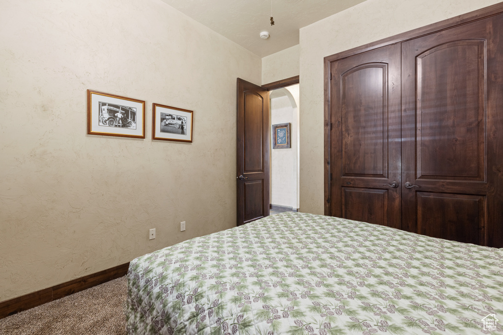 Carpeted bedroom with arched walkways and baseboards