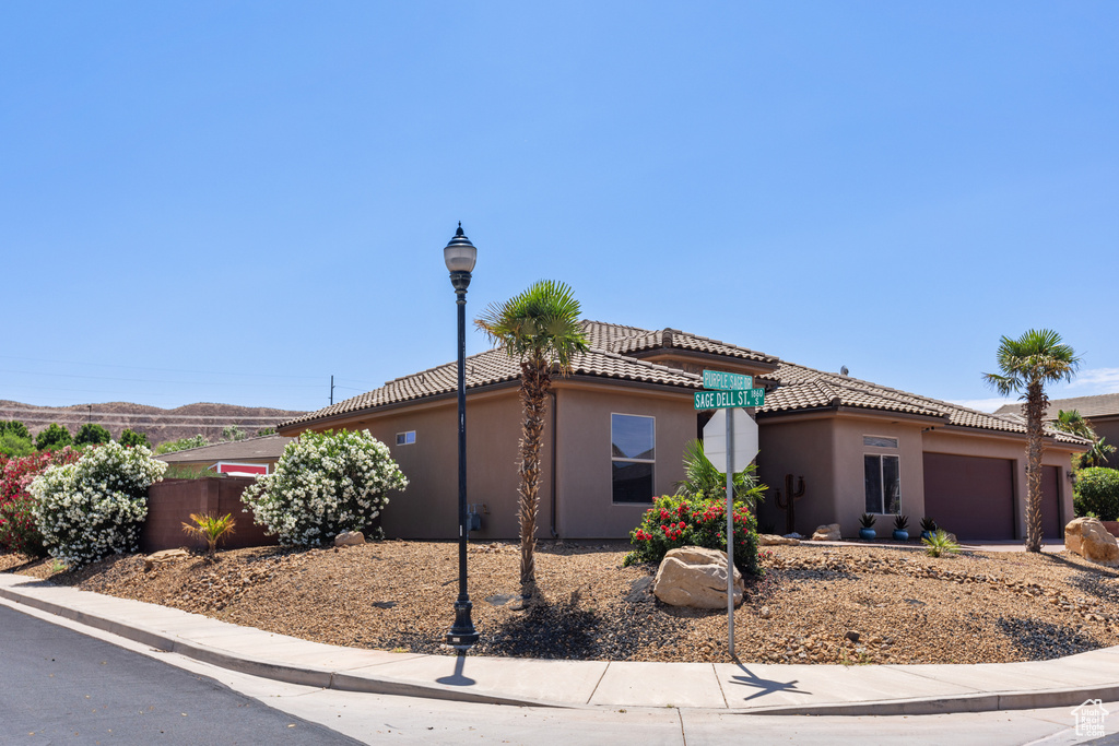 View of front of house with an attached garage, stucco siding, and a tiled roof