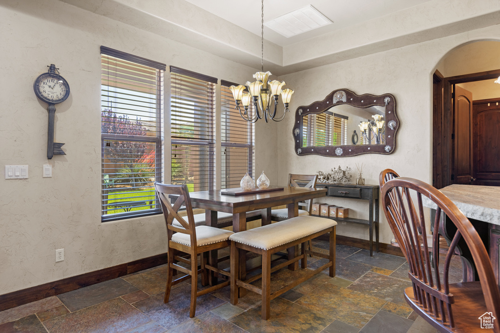 Dining space with stone tile floors, arched walkways, and a chandelier