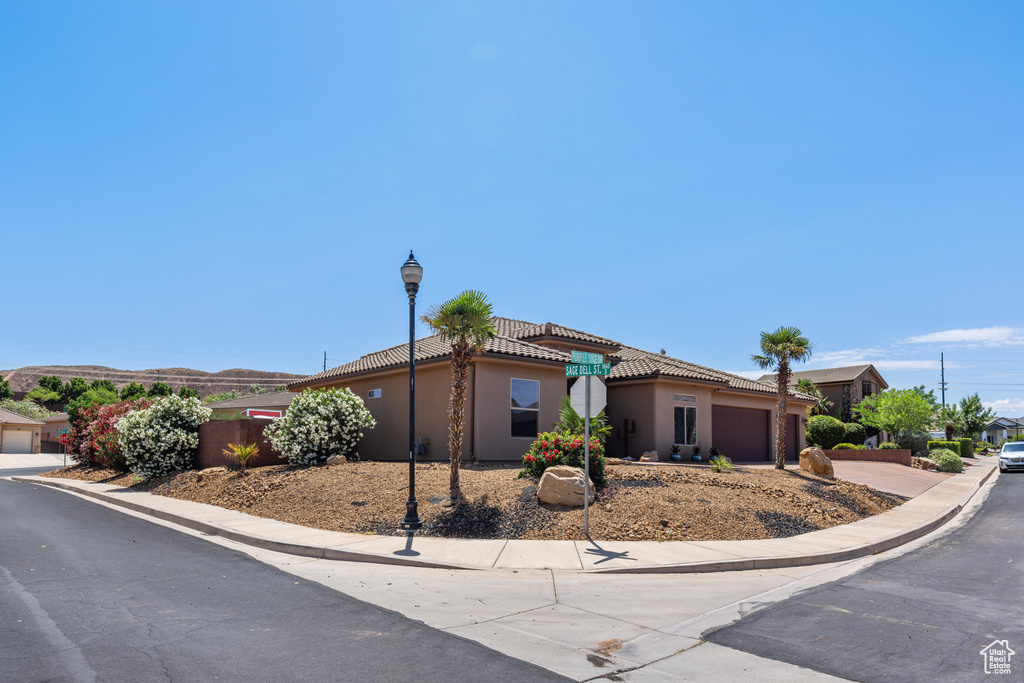 View of front facade with a garage, stucco siding, a tile roof, and driveway