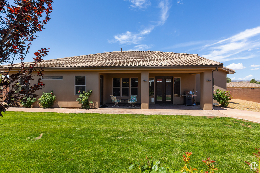 Rear view of property with a tiled roof, stucco siding, and a patio