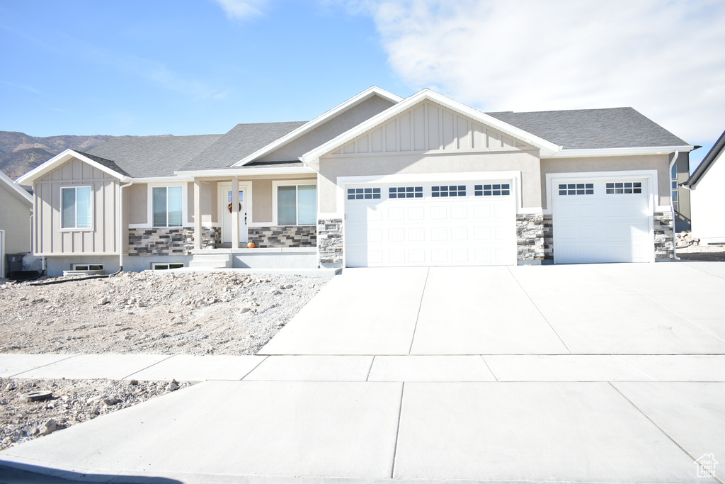 View of front of property with an attached garage, board and batten siding, concrete driveway, and stone siding
