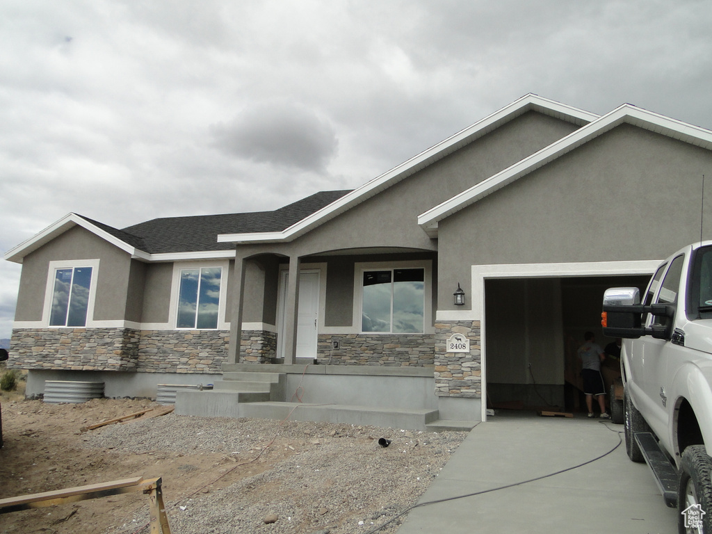 Ranch-style home with stone siding, stucco siding, an attached garage, and concrete driveway