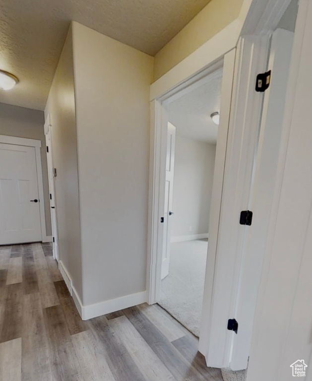 Corridor with wood finished floors and a textured ceiling