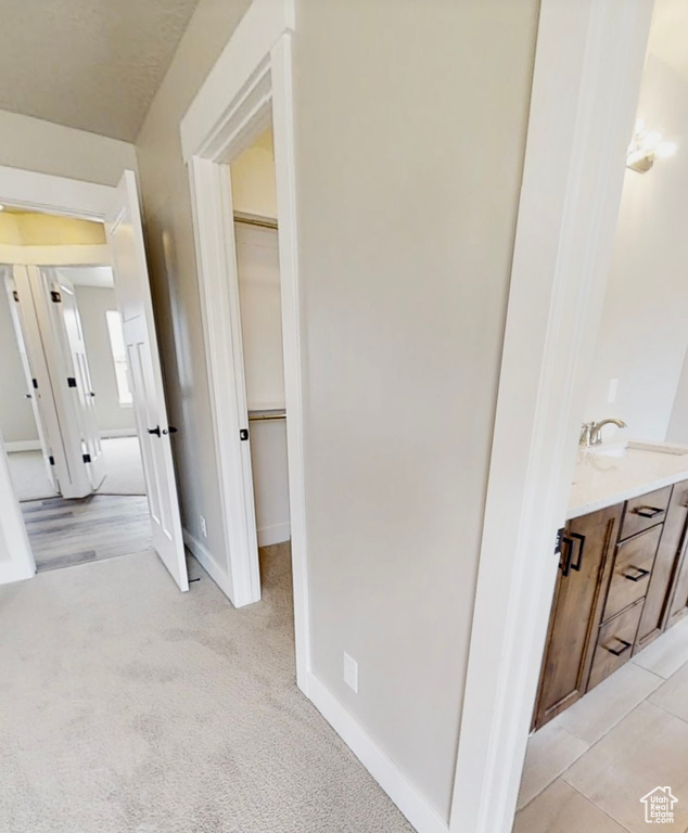 Hall featuring a sink and light colored carpet
