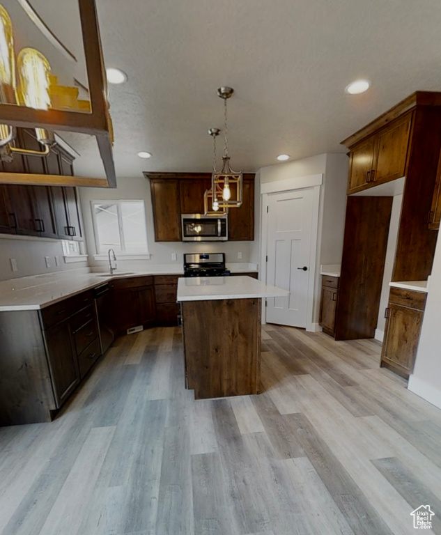 Kitchen featuring appliances with stainless steel finishes, a chandelier, a center island, light wood-style flooring, and recessed lighting