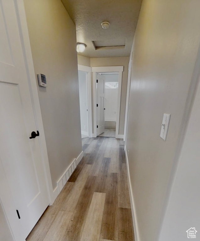 Corridor with attic access and light wood-type flooring