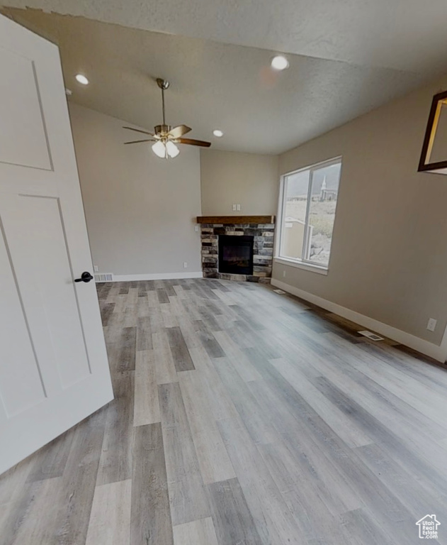 Unfurnished living room featuring ceiling fan, light wood-style flooring, recessed lighting, and a stone fireplace