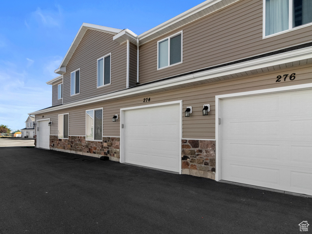 View of property exterior with stone siding and a garage