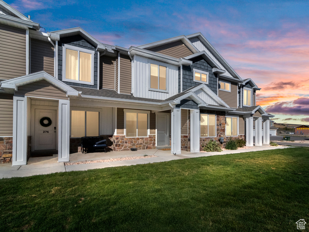 View of front of property with a lawn, stone siding, and board and batten siding