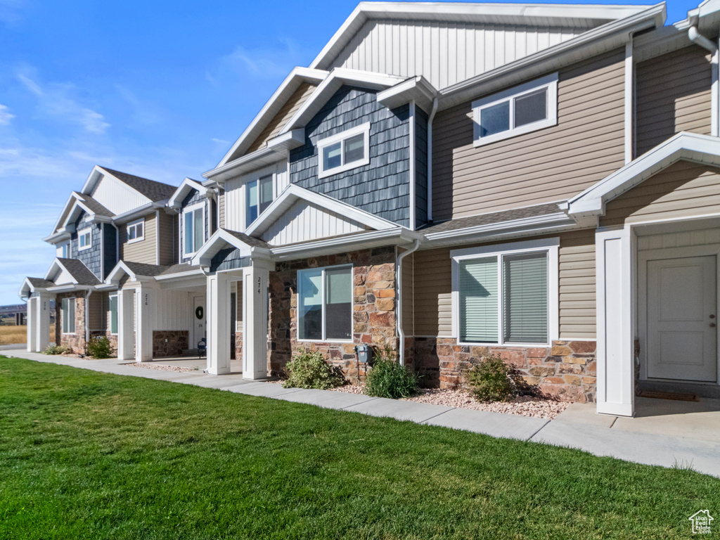 View of front of house with a front yard, stone siding, and board and batten siding