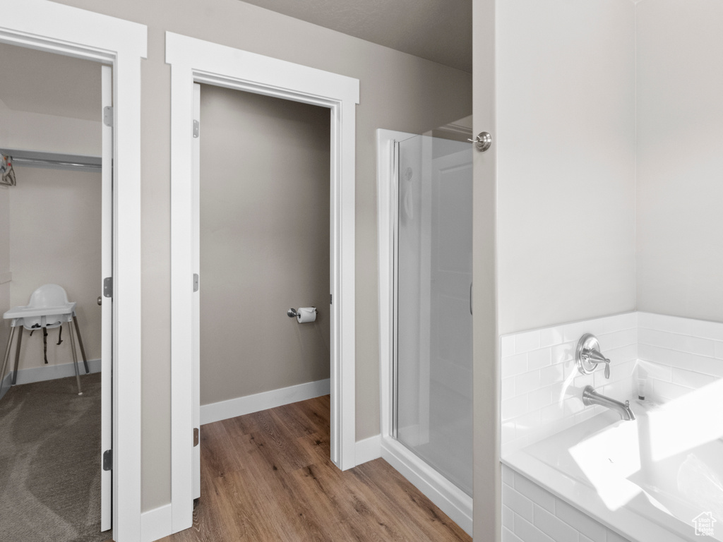 Full bathroom featuring a bath, wood finished floors, and a shower stall