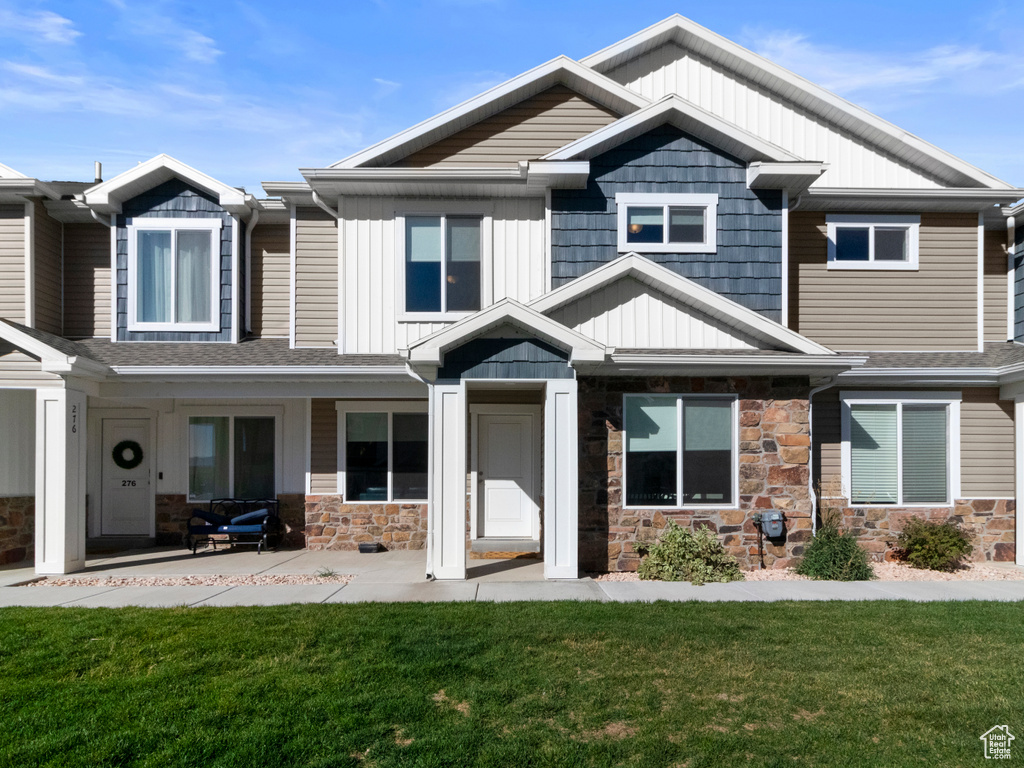 View of front of home featuring stone siding, a front yard, and board and batten siding