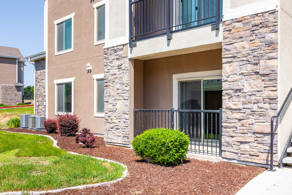 View of side of property featuring stone siding, stucco siding, and a balcony