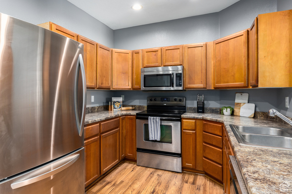 Kitchen featuring appliances with stainless steel finishes, light wood-style flooring, brown cabinets, and recessed lighting