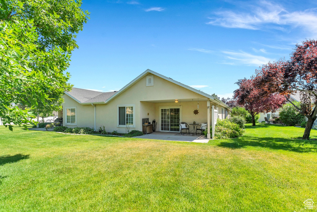 Rear view of house with stucco siding, a patio area, and a yard