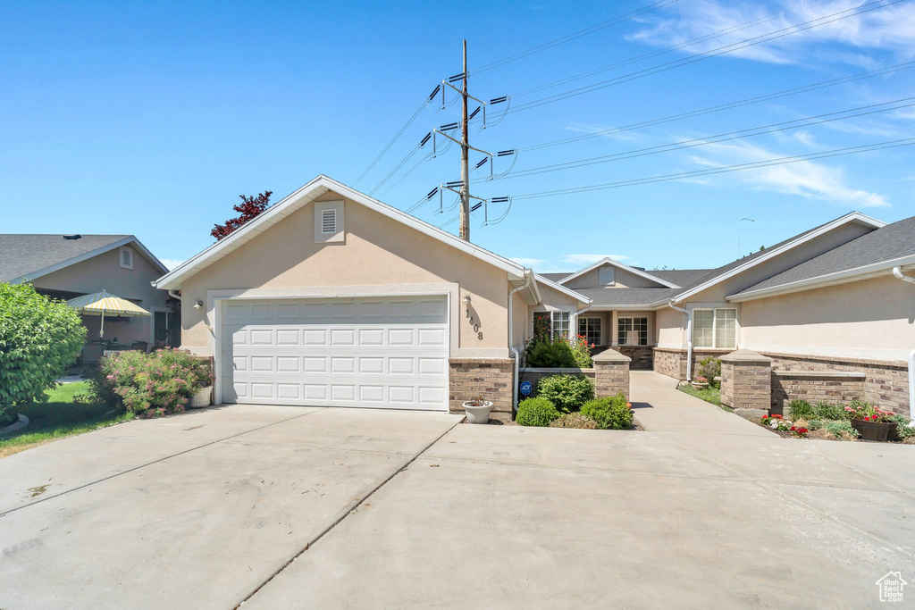 Ranch-style home featuring concrete driveway, an attached garage, stucco siding, and brick siding