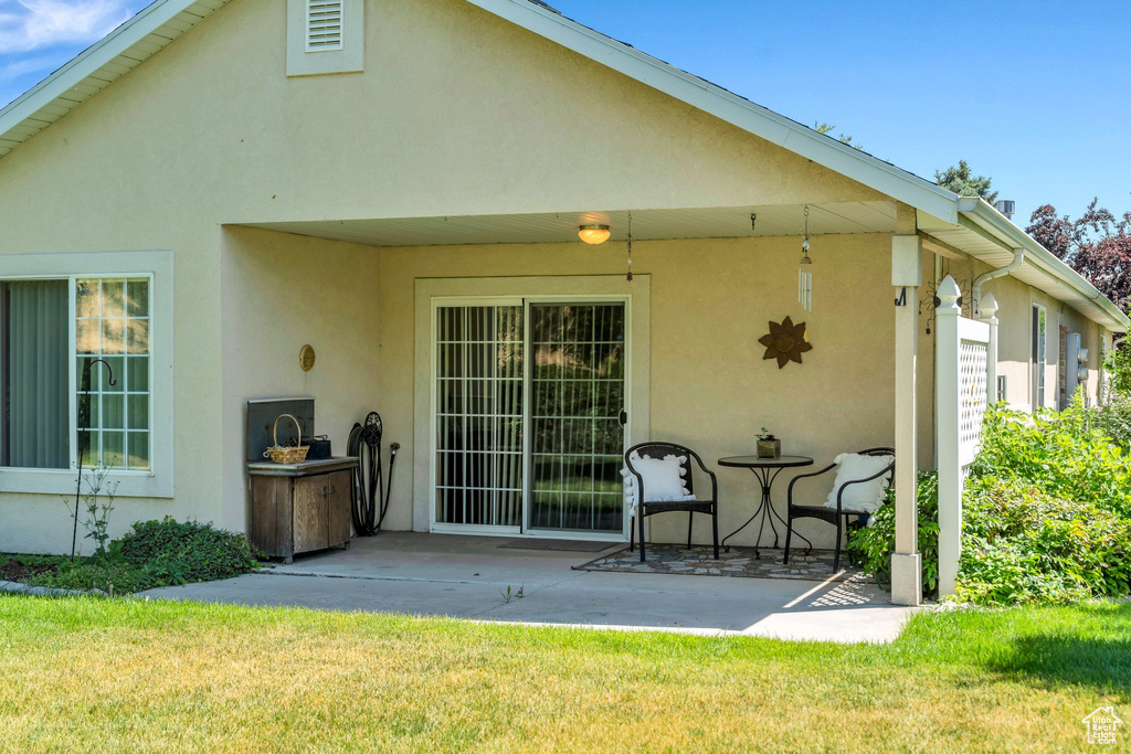 Back of house featuring stucco siding, a patio area, and a yard
