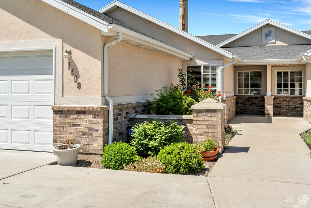Doorway to property featuring stucco siding, an attached garage, and driveway