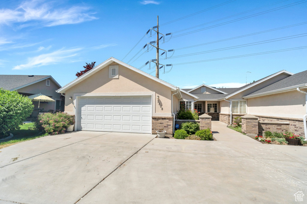 Ranch-style home featuring concrete driveway, an attached garage, brick siding, and stucco siding
