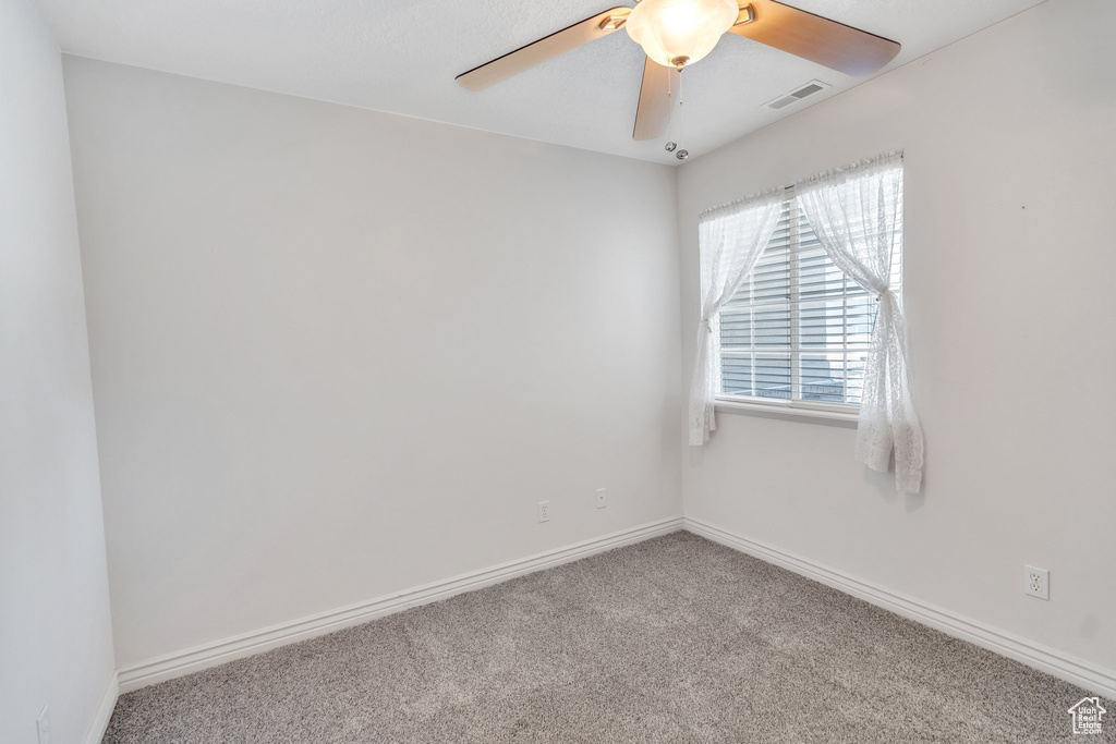 Carpeted spare room featuring a ceiling fan and baseboards