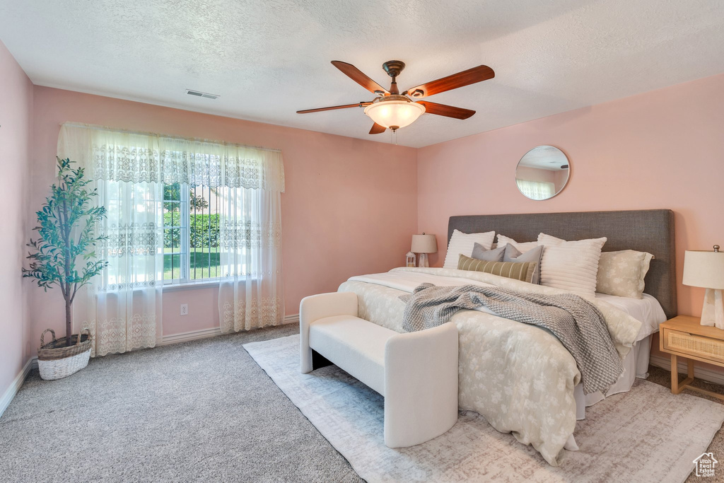 Carpeted bedroom featuring a ceiling fan and a textured ceiling