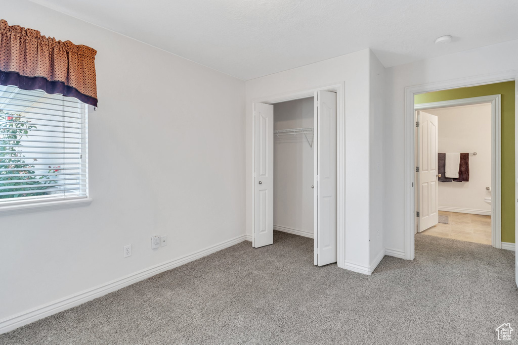 Unfurnished bedroom featuring light carpet and a closet