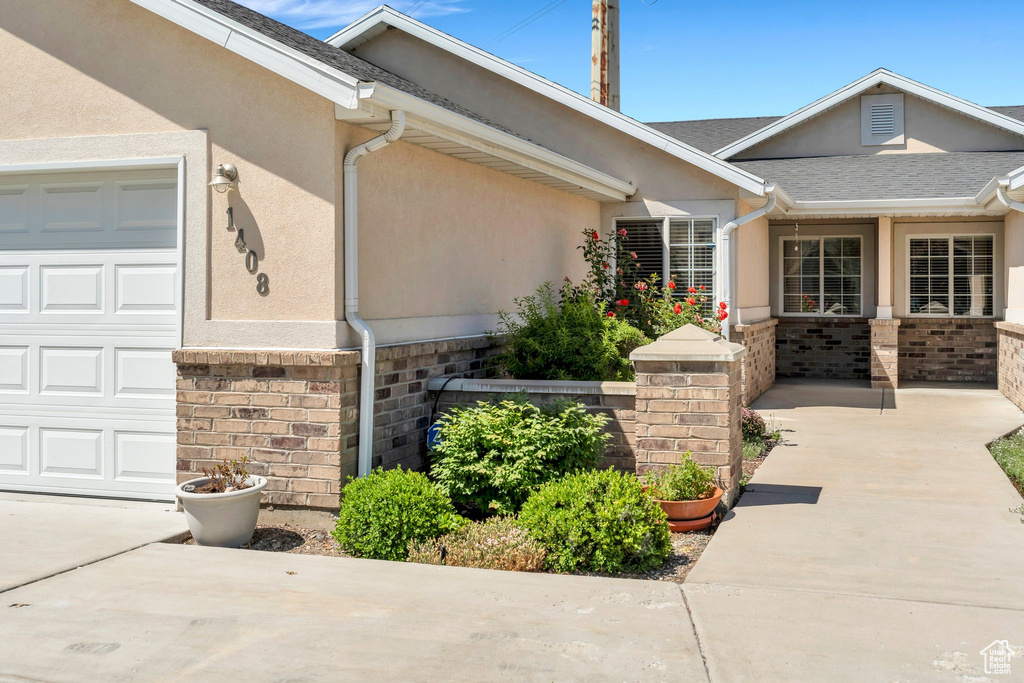Property entrance featuring stucco siding, an attached garage, and concrete driveway