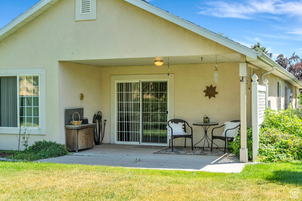 Rear view of house with stucco siding, a patio, and a yard