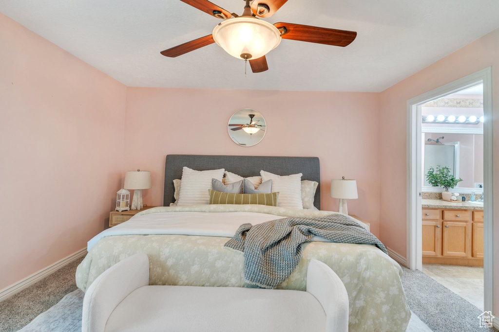 Bedroom featuring light carpet, ensuite bathroom, and a ceiling fan