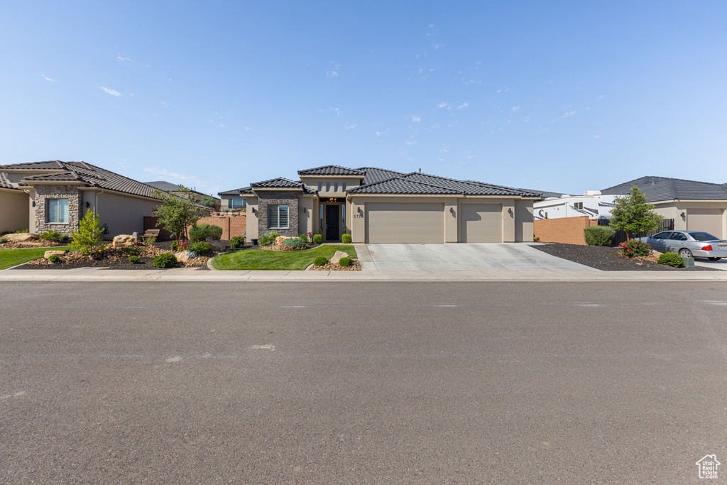 View of front of home with a garage, driveway, a tiled roof, stucco siding, and a residential view