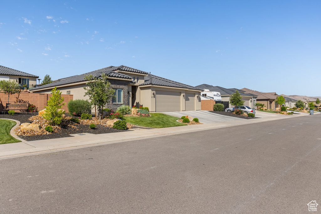 View of front of property featuring a garage, concrete driveway, stucco siding, a tile roof, and a residential view