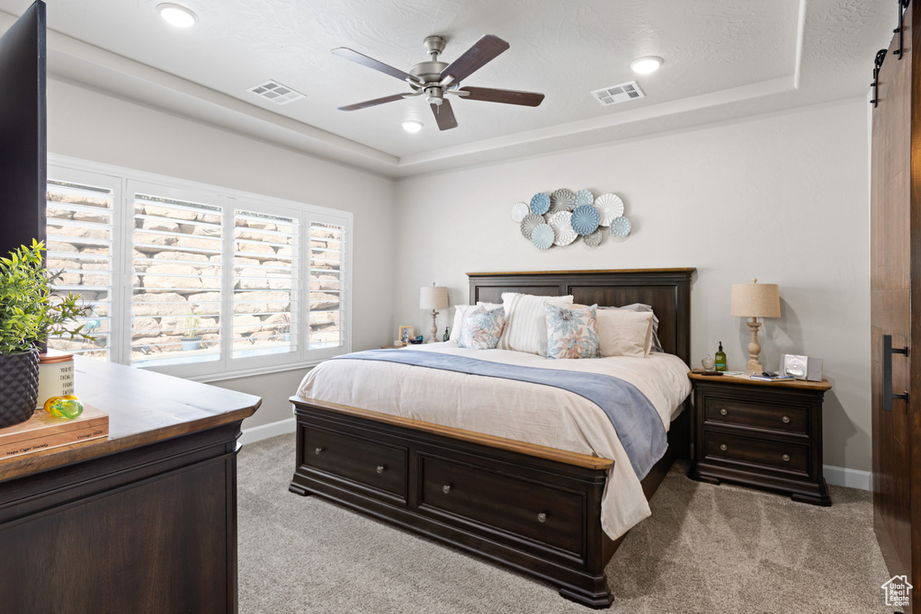 Bedroom featuring light colored carpet, a tray ceiling, ceiling fan, and recessed lighting