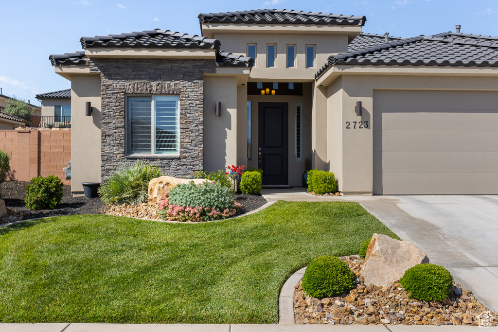 Mediterranean / spanish-style home featuring stucco siding, concrete driveway, stone siding, an attached garage, and a tiled roof