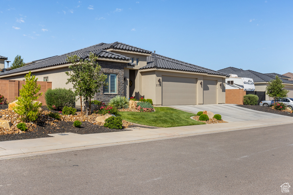 Prairie-style house featuring an attached garage, stucco siding, a tile roof, driveway, and stone siding