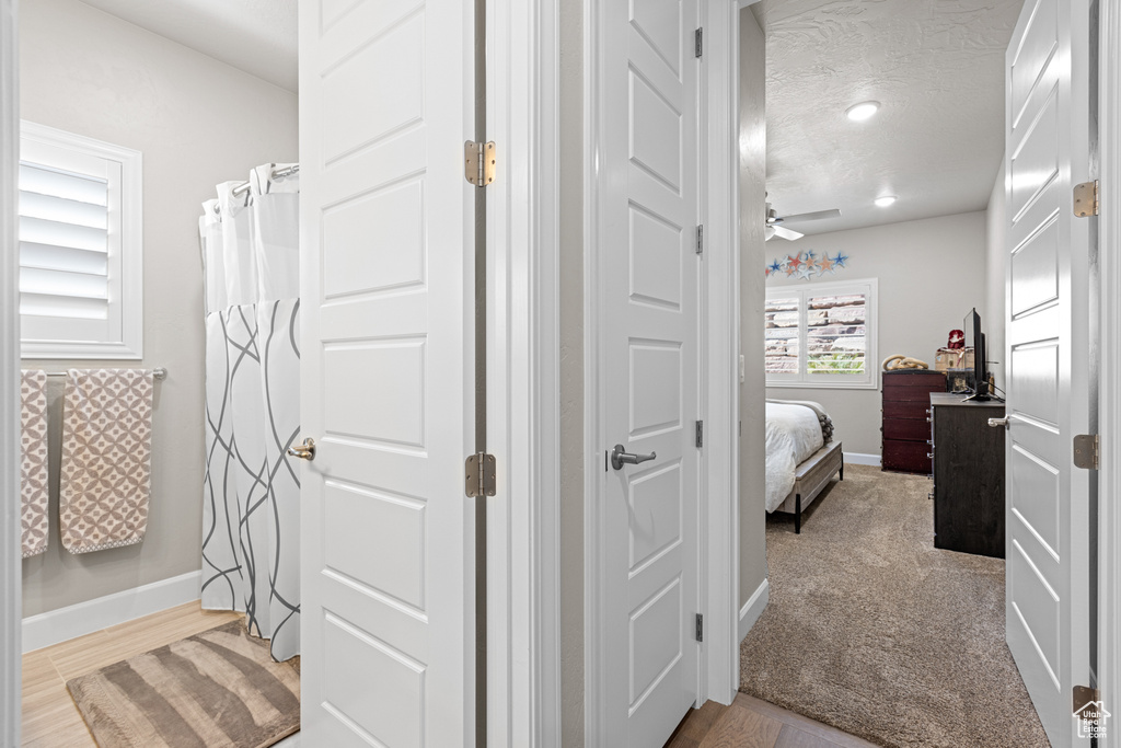Full bathroom with ceiling fan, connected bathroom, a textured ceiling, and wood finished floors
