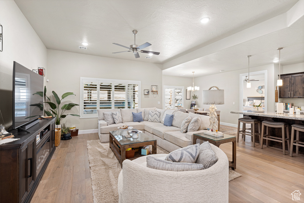 Living area featuring ceiling fan, light wood-style flooring, a chandelier, and recessed lighting