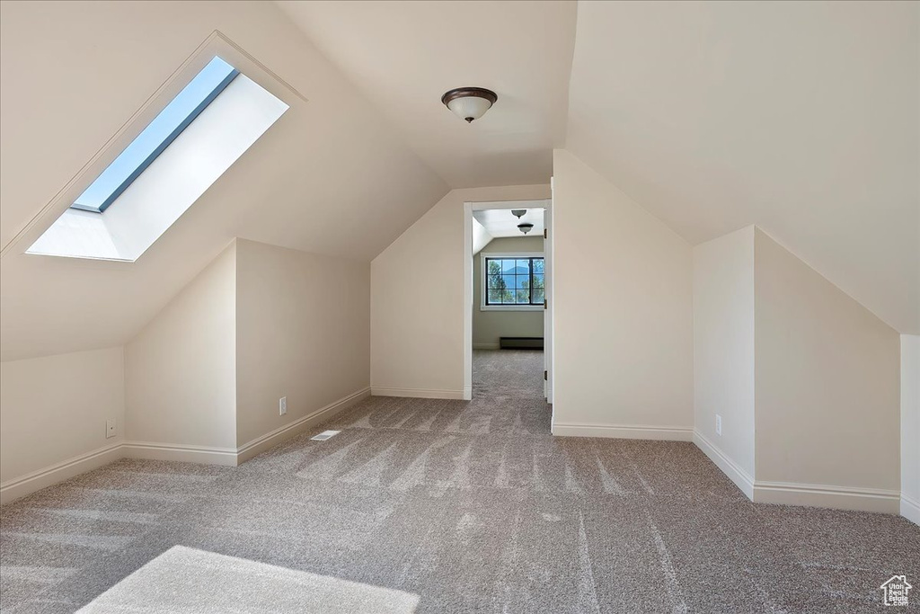 Additional living space with a skylight, carpet, and vaulted ceiling
