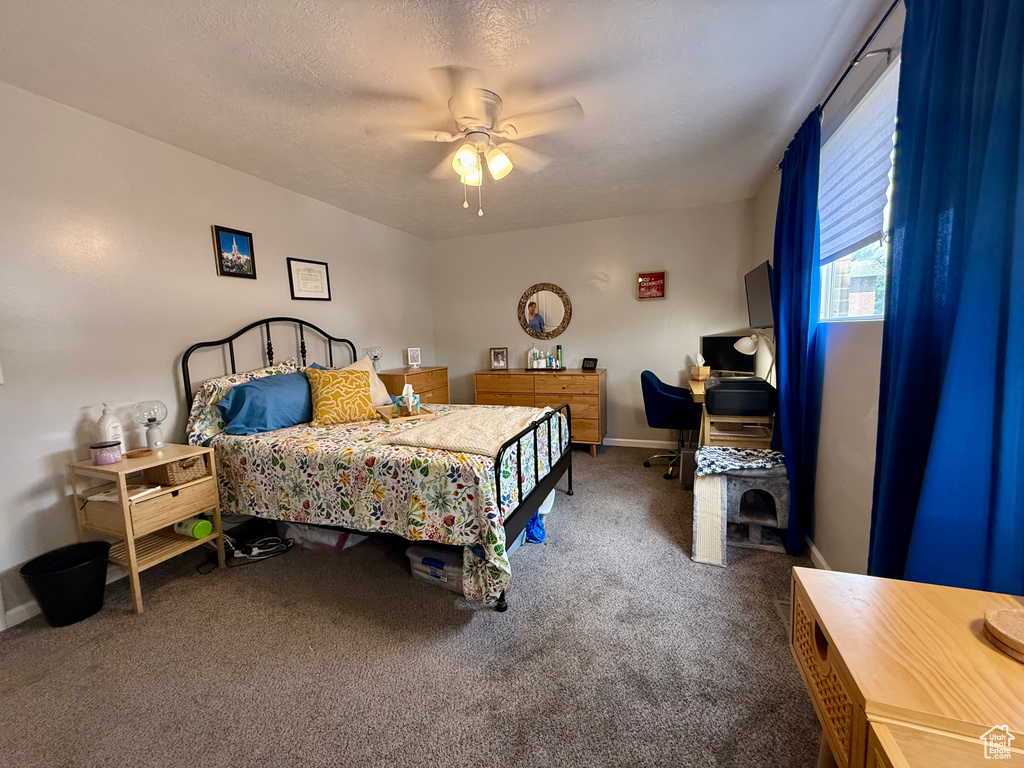 Carpeted bedroom featuring an office area and ceiling fan
