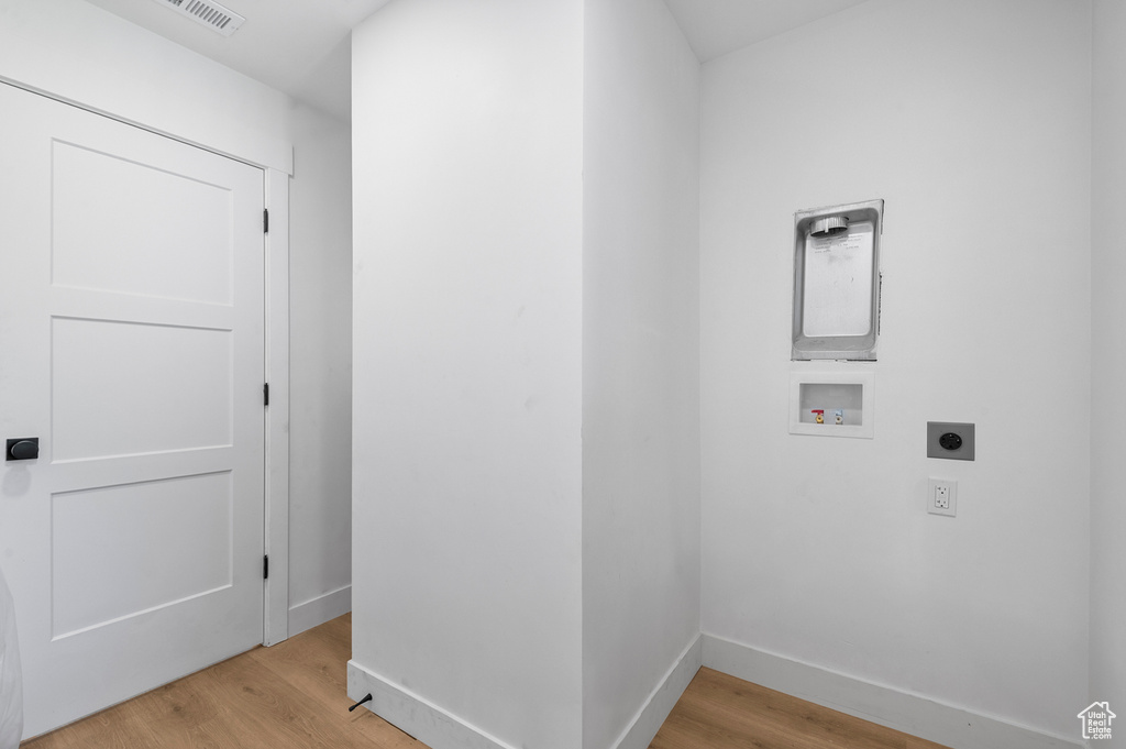 Laundry area with electric dryer hookup, hookup for a washing machine, and light wood-style floors
