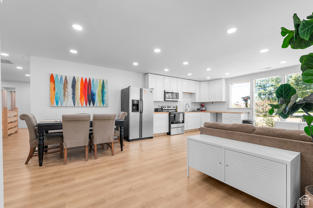 Living area with light wood finished floors and recessed lighting