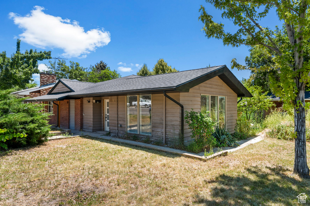 Ranch-style house with a front yard, a chimney, and roof with shingles