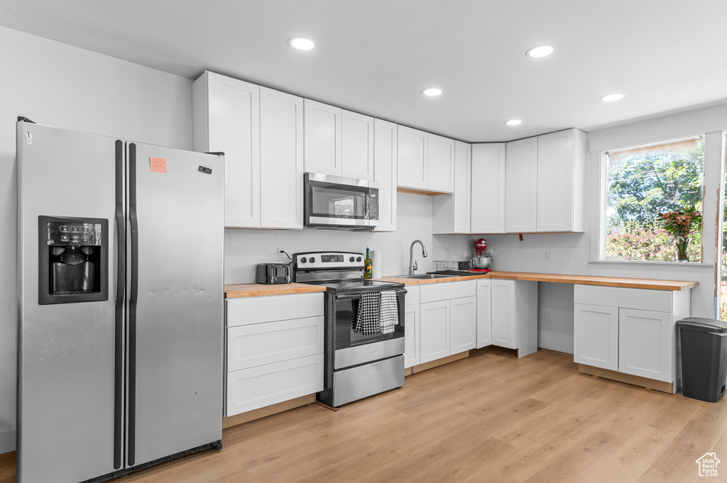 Kitchen with appliances with stainless steel finishes, wood counters, white cabinetry, and recessed lighting