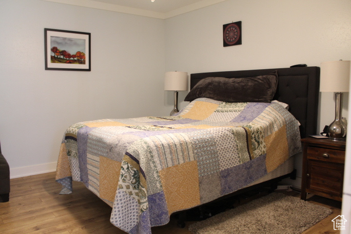 Bedroom featuring wood finished floors and crown molding