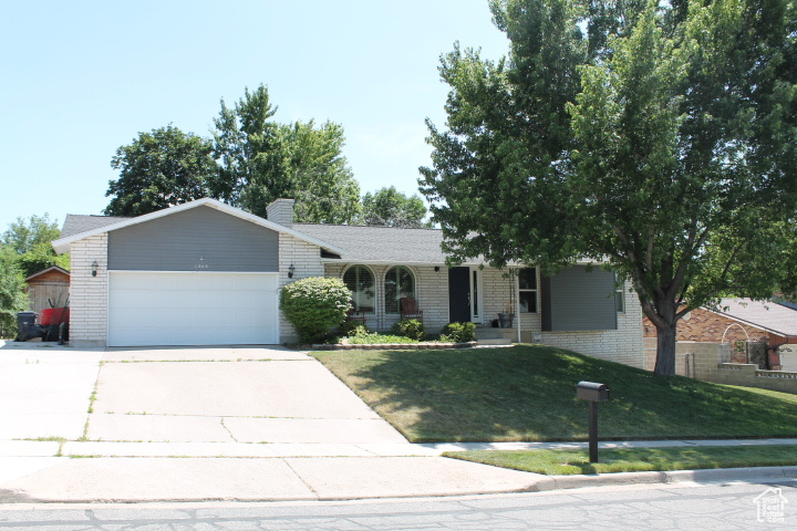 Ranch-style house with brick siding, an attached garage, a front lawn, and driveway